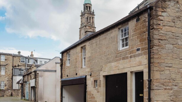 A stone building with a tower, a cobblestone street, and a clear sky. - Charming Central Mews Home with Secure Parking (Edinburgh)