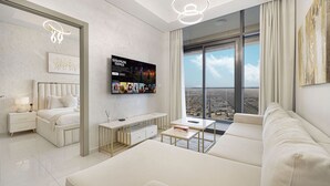 Ein modernes Hotelzimmer mit einem großen Bett, einer Couch, einem Fernseher und Blick auf die Stadt.
