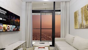 Ein modernes Wohnzimmer mit Blick auf die Stadt, einem Flachbildfernseher, einer Couch und einem Couchtisch.