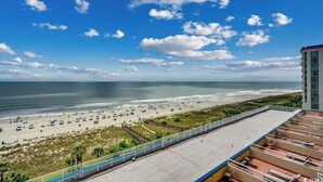 Vista de la playa desde un balcón de hotel, con cielo despejado y océano.