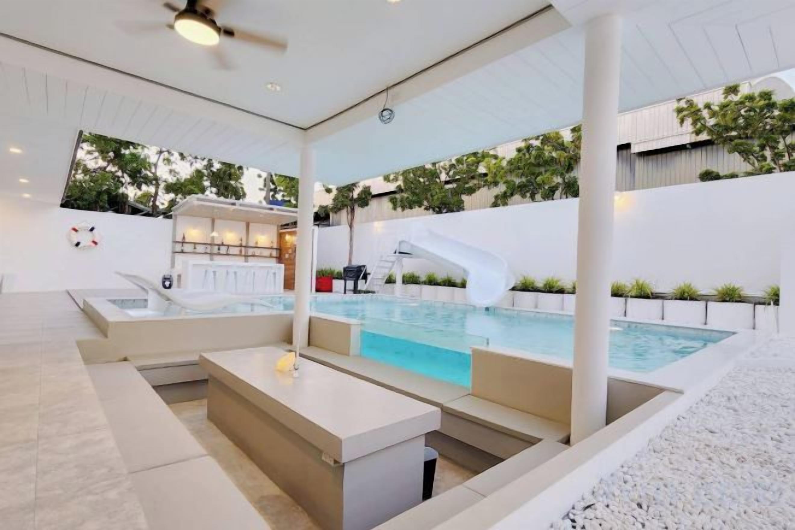 A modern indoor pool area with a lounge, a slide, and a bar area.