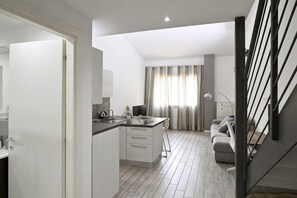Eine moderne Küche mit Kochinsel, einem Essbereich inklusive Sofa und einer Treppe.