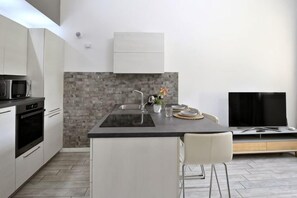 A modern kitchen with a black countertop, white cabinets, a built-in oven, and a stone backsplash. - Boutique Apartment Florence “Diviso Due” (Florence)