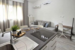 A modern kitchen with a central island, a dining area with a sofa, and a workspace with a chair. - Boutique Apartment Florence “Diviso Due” (Florence)