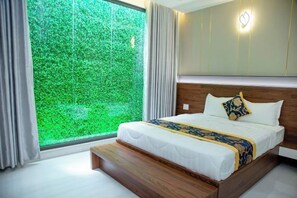 Een hotelkamer met een groot raam, een bed met een beddeken met een patroon en een houten hoofdbord.