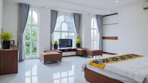 Een moderne hotelkamer met een groot bed, een bureau met een televisie en twee zithoeken.