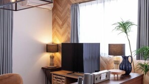 Un salon moderne avec un téléviseur, un meuble en bois, une lampe et une plante.