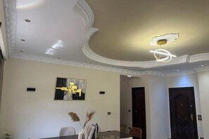 A hotel lobby with a dining area, a reception desk, and a modern chandelier. - Chessboard Oasis - Elite 2BR apart by BC residence (New Cairo City)