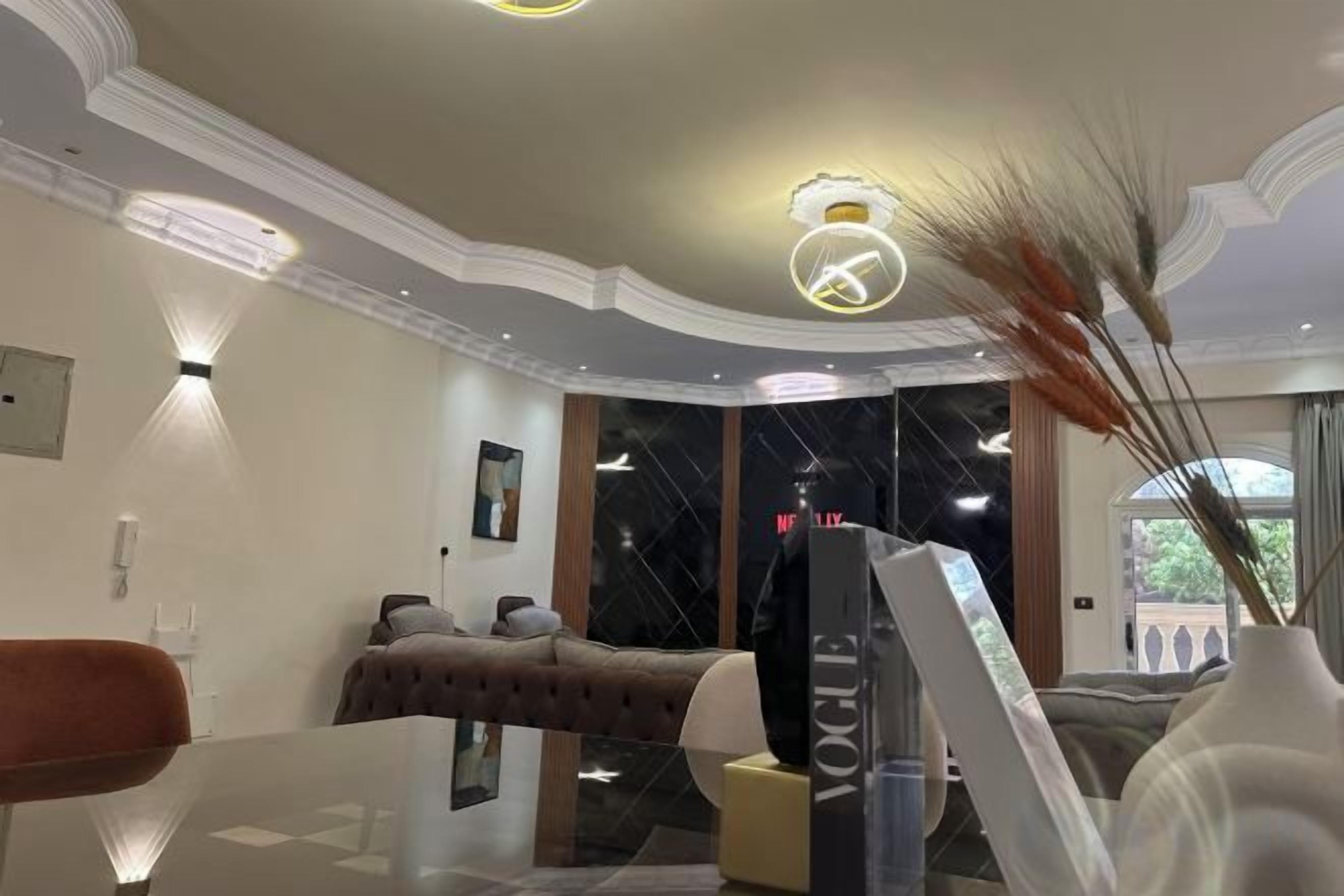A modern living room with a glass coffee table, a sofa, a television, and a decorative vase.