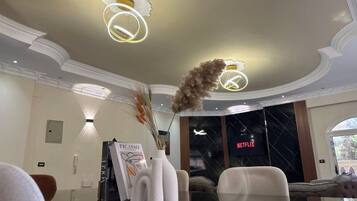Un interior moderno con una mesa de vidrio, jarrones blancos y un cartel de Netflix en la pared.