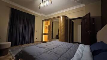 Habitación de hotel con una cama grande, un rincón de estar con una silla, un armario y un espejo.