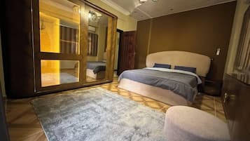 Un dormitorio con una cama grande, un armario y un espejo.