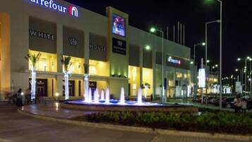 A Carrefour store at night with a fountain in front.