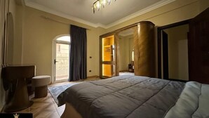 A bedroom with a large bed, a wardrobe, a mirror, and a door leading to a balcony. - Chessboard Oasis - Elite 2BR apart by BC residence (New Cairo City)