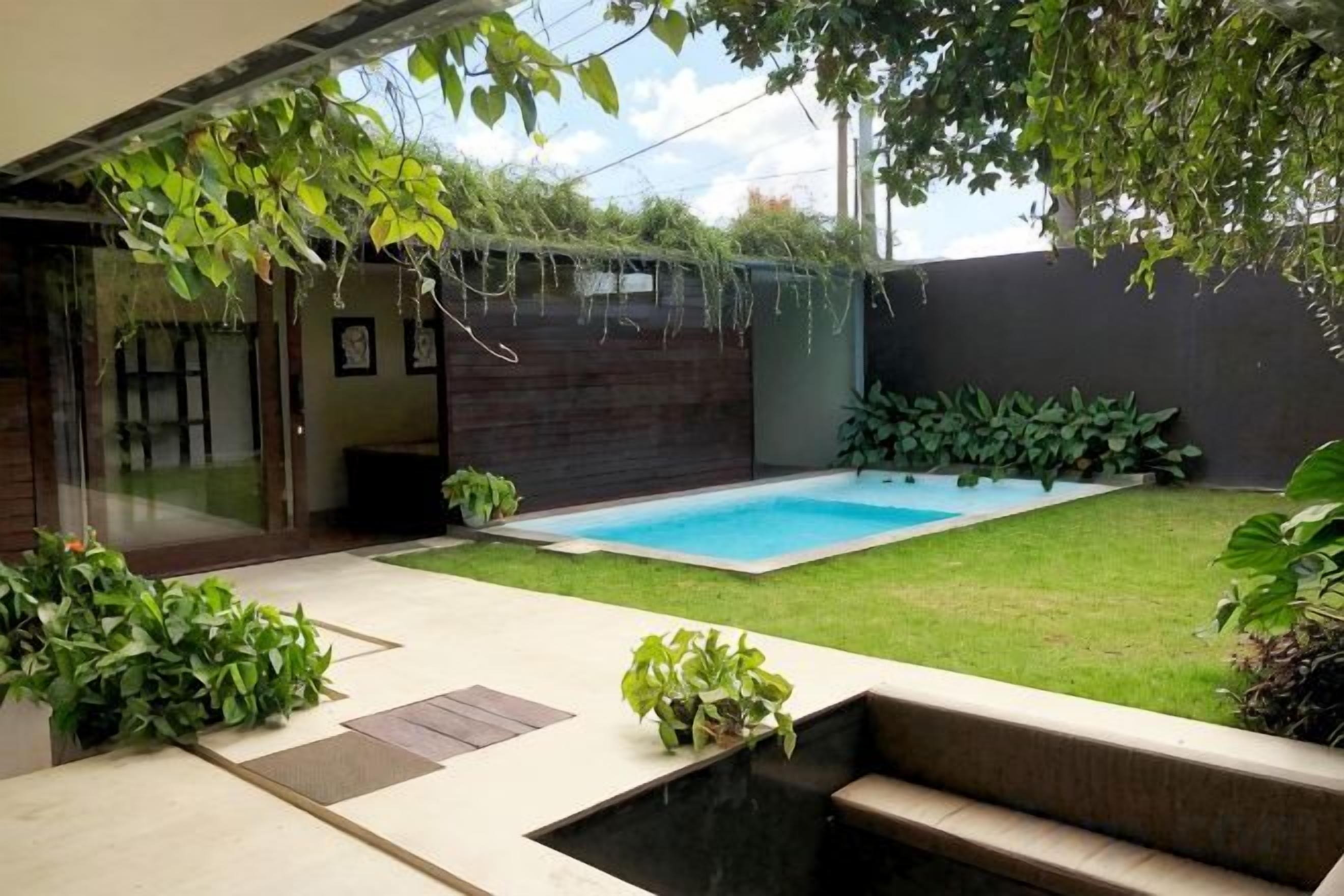 A backyard with a swimming pool, a wooden deck, and potted plants.