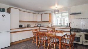 A compact kitchen with white cabinets, a wooden dining table, and a stove.