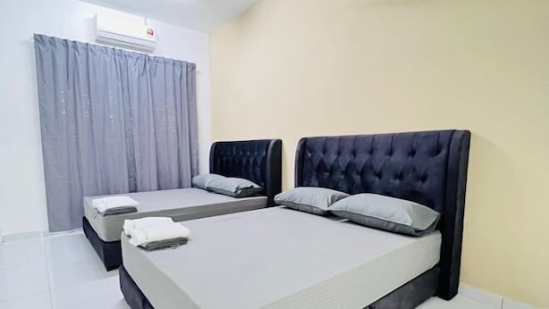A hotel room with two beds, a grey curtain, and an air conditioning unit. - Kulai 3B2R Indahpura Landed House Near JPO (Kulai)