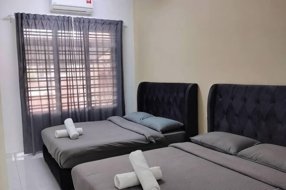 Ein Hotelzimmer mit zwei Betten, einem Fenster mit durchsichtigen Vorhängen und einer Wand-Klimaanlage.
