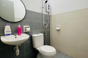 Un baño con lavamanos, inodoro y espejo.