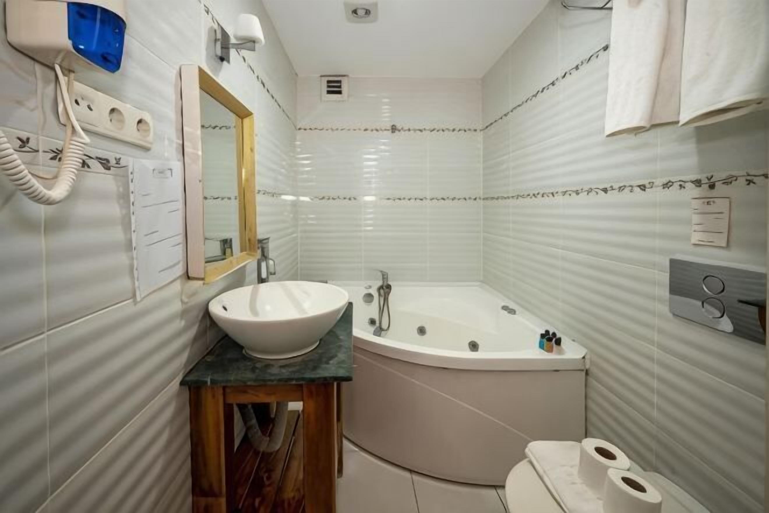 A bathroom with a sink, mirror, vanity, bathtub, toilet, and towel rack.