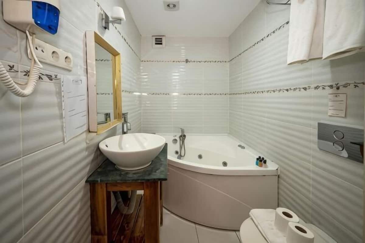 A bathroom with a sink, mirror, vanity, bathtub, toilet, and towel rack.