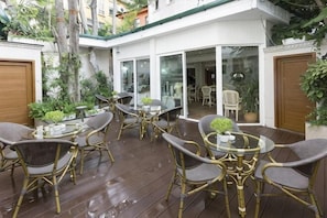 A patio with wicker furniture, a glass table, and potted plants. - Fuat Bey Palace Hotel & Suites (Istanbul)