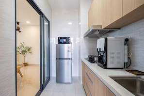 A modern kitchen with a stainless steel refrigerator, a coffee machine, and wooden cabinets. - Aradia by FEEL HOME (Kuala Lumpur)