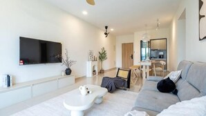 A modern living room with a flat-screen TV, a white coffee table, a sofa, and a cat. - Aradia by FEEL HOME (Kuala Lumpur)