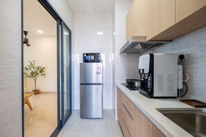 A modern kitchen with a stainless steel refrigerator, a coffee machine, and a sink.