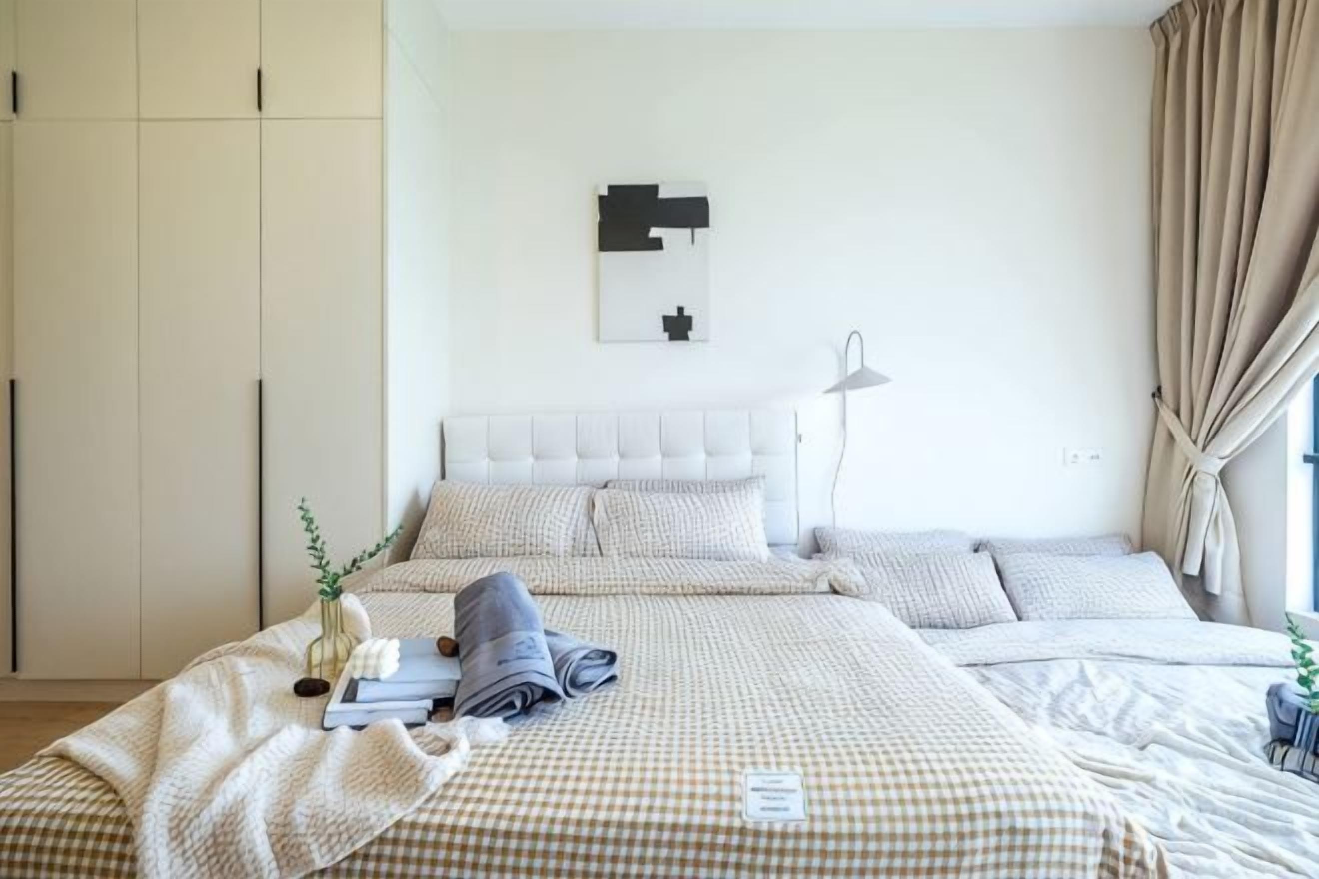 A bedroom with a bed, bedside tables, a wardrobe, and a wall-mounted light fixture.
