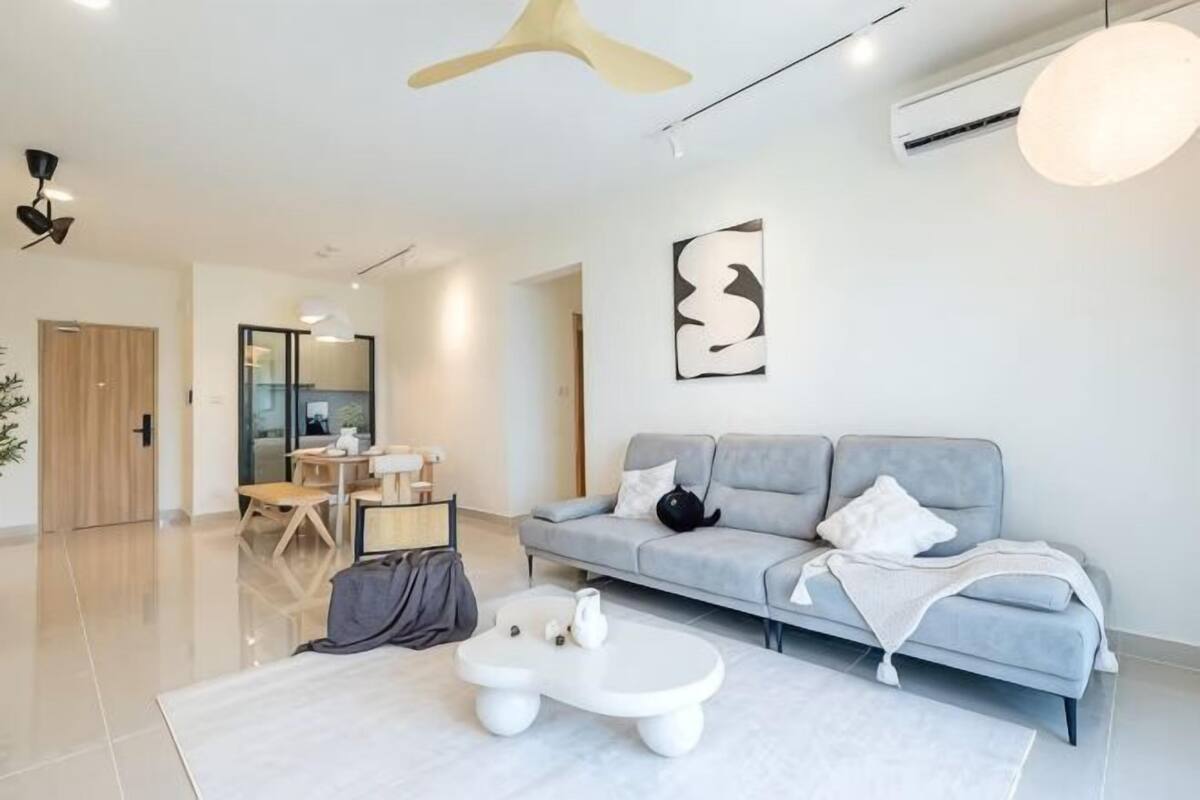 Un soggiorno moderno con un divano grigio, un tavolino bianco e una ventola a soffitto.