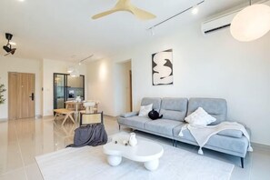 A modern living room with a sofa, a coffee table, and a dining area. - Aradia by FEEL HOME (Kuala Lumpur)