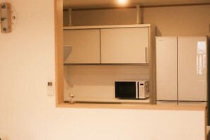 Eine kleine Küche mit einer Mikrowelle, einem Kühlschrank und einer Wanduhr.