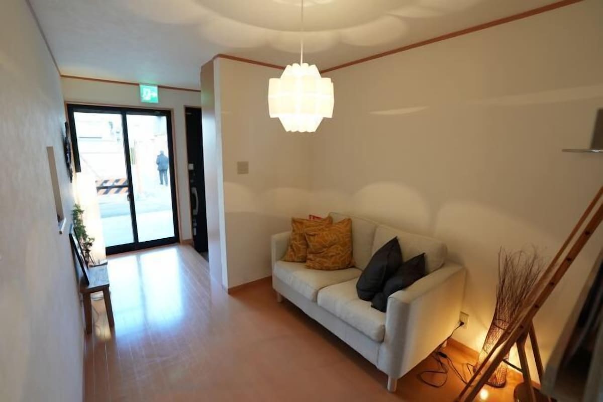 A reception area with a sofa, a hanging light fixture, and a staircase.