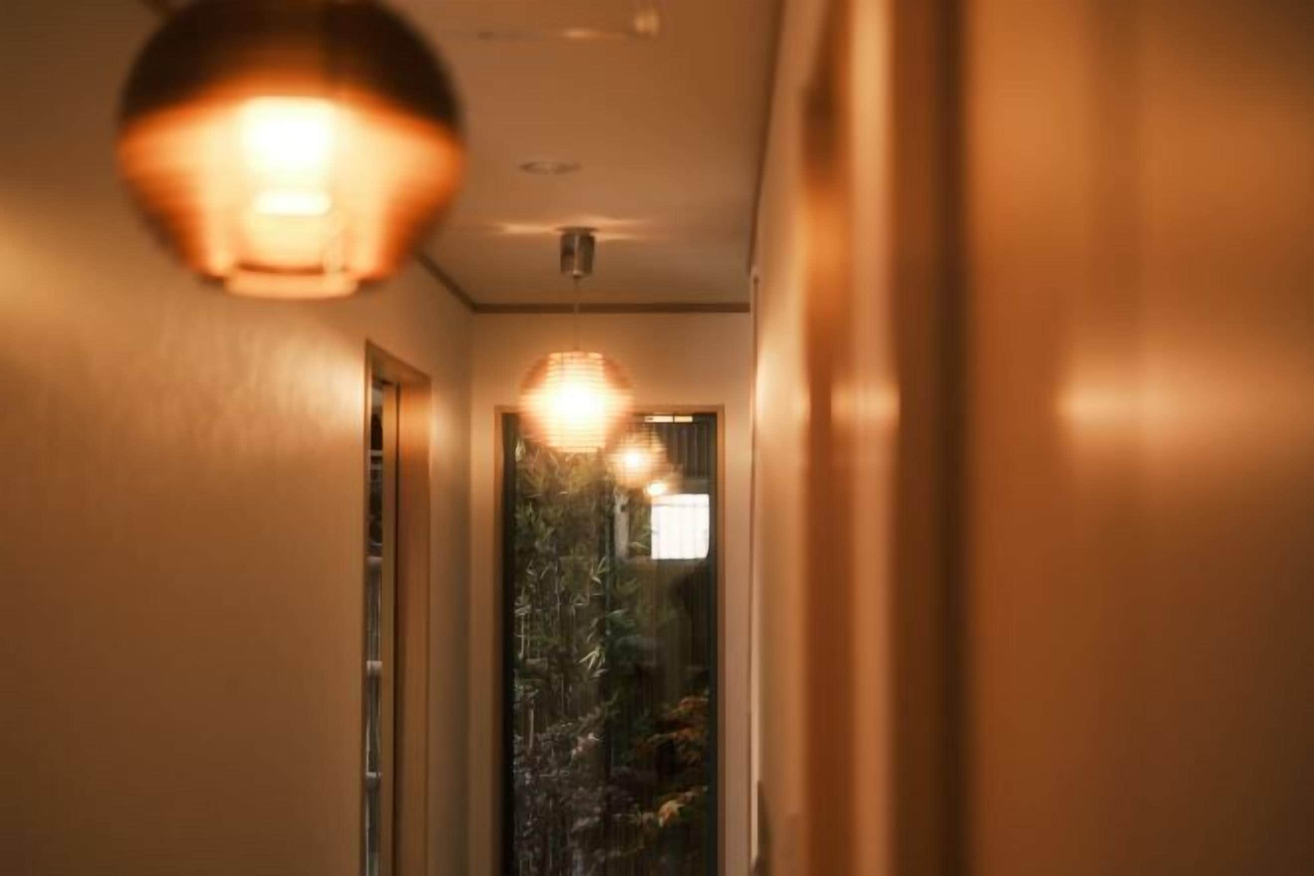 Un couloir avec un luminaire au plafond et une porte donnant sur une pièce.