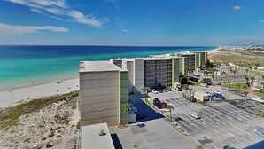 A hotel with multiple floors, a parking lot, and a view of the beach and ocean.