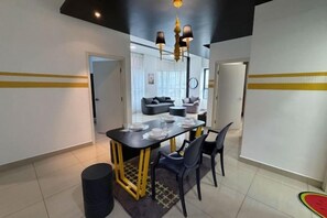 A dining area with a black table and chairs, a chandelier, and a patterned rug. - ARTE@AMPANG (Ampang)
