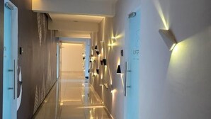 A modern hotel corridor with a sleek design, featuring a long, reflective floor and wall-mounted lighting fixtures. - ARTE@AMPANG (Ampang)