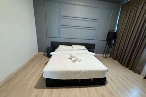 A neatly made bed with a white comforter and pillows, a dark headboard, and a wooden floor. - ARTE@AMPANG (Ampang)