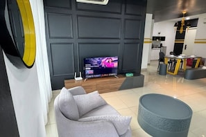 A modern living room with a grey sofa, a round coffee table, and a flat-screen TV mounted on a dark wall. - ARTE@AMPANG (Ampang)