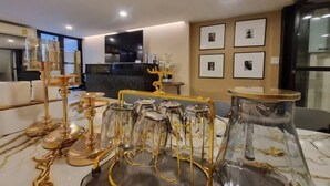 A modern dining area with a glass table set with wine glasses and gold-rimmed candle holders. - Oliver's House in Kaset (Bangkok)