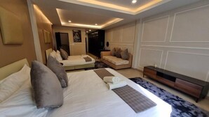 A hotel room with two beds, a sofa, a TV, and a wooden cabinet. - Oliver's House in Kaset (Bangkok)