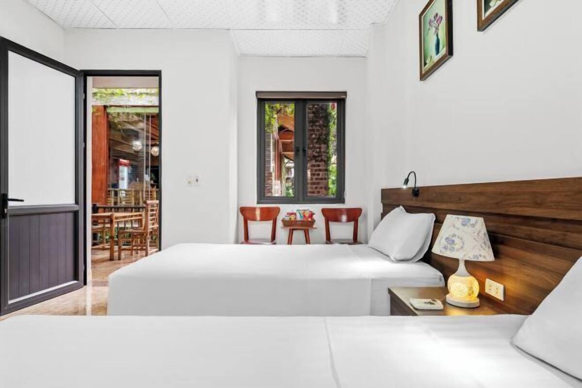 A bedroom with a bed, bedside table, lamp, and two chairs.