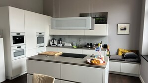 Eine moderne Küche mit weißen Schränken, einem Einbauofen, einer Mikrowelle, einer Kaffeemaschine und einem Toaster.
