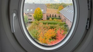 Ein rundes Fenster mit Blick auf ein Gebäude und einen Garten.