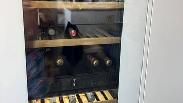 Ein Weinkühlschrank mit mehreren Ablagen, einer digitalen Temperaturanzeige und einer Weinflasche auf der untersten Ablage.