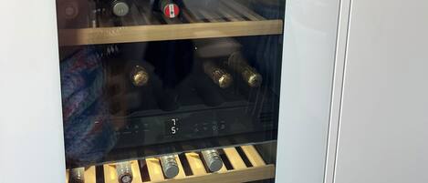 Un réfrigérateur à vin doté de plusieurs étagères, d’un affichage numérique de la température et d’une bouteille de vin placée sur l’étagère inférieure.