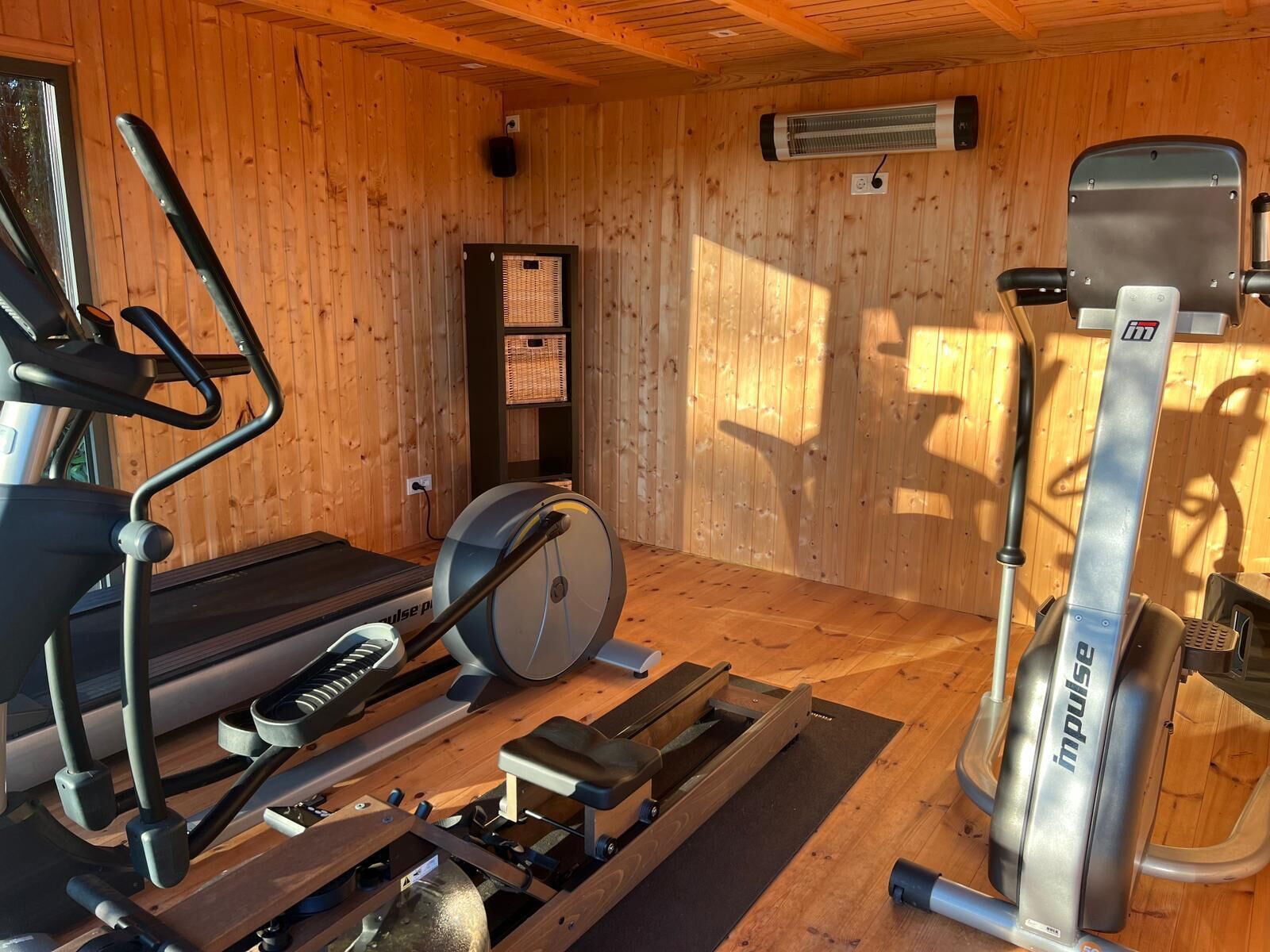 A gym with a treadmill, stationary bike, and elliptical machine.
