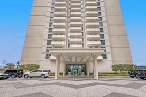 Un hôtel de grande hauteur avec une entrée principale, de nombreux étages et un espace de stationnement situé à l’avant.