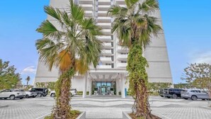 Ein hohes Hotel mit modernem Design, dessen zentraler Eingang von Palmen gesäumt wird.